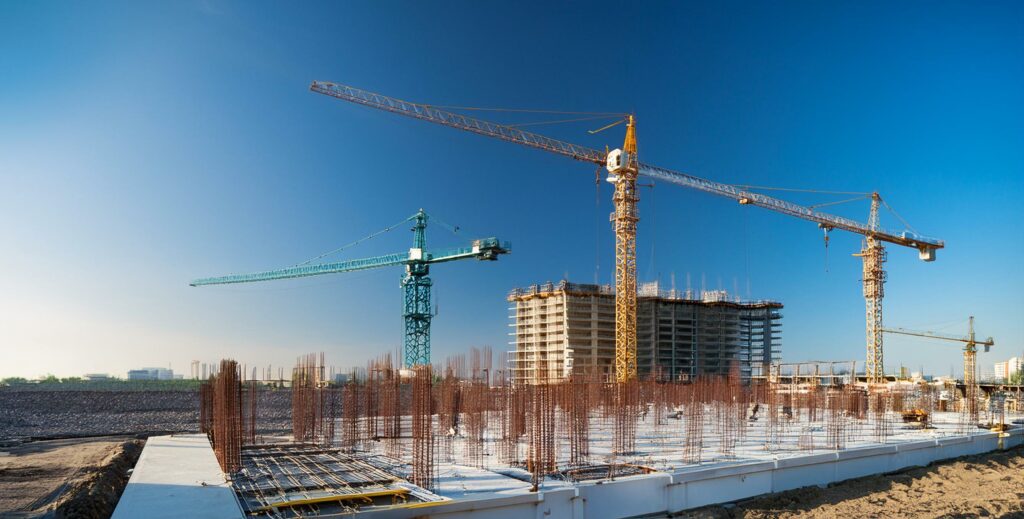 Commercial building site that's near finished with cranes with lots of negative space above