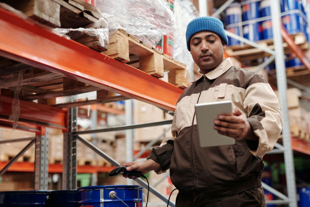 Worker checks inventory on a tablet in an industrial warehouse